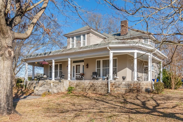 farmhouse inspired home featuring covered porch and a chimney