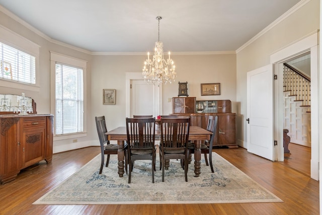 dining room with an inviting chandelier, ornamental molding, wood finished floors, and stairway