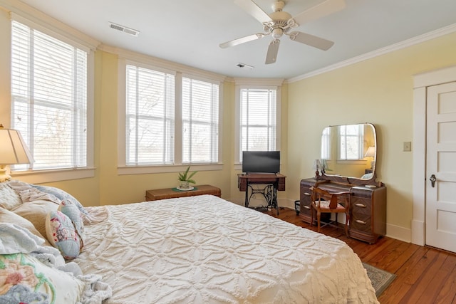 bedroom with visible vents, ornamental molding, ceiling fan, and wood finished floors