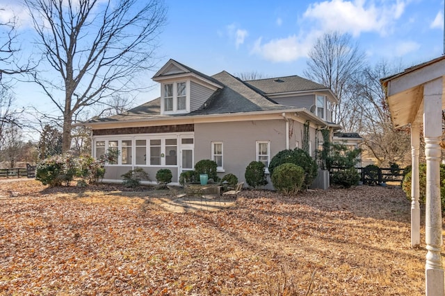 rear view of house featuring a sunroom, a shingled roof, and fence
