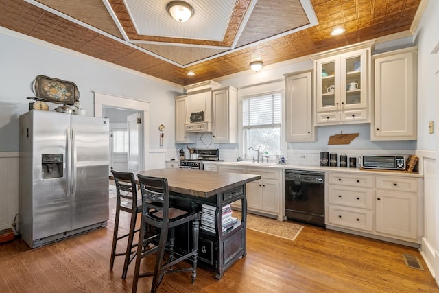 kitchen featuring crown molding, appliances with stainless steel finishes, an ornate ceiling, visible vents, and glass insert cabinets