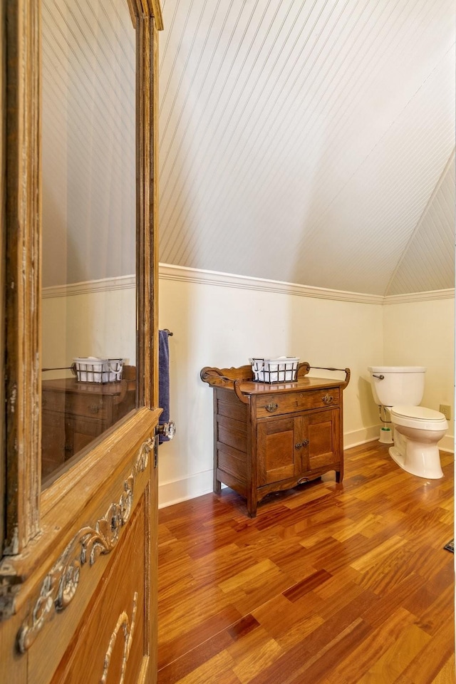 half bathroom featuring baseboards, vaulted ceiling, toilet, and wood finished floors