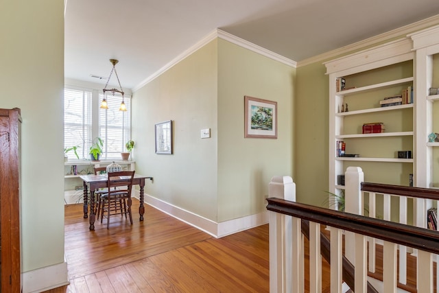 corridor featuring crown molding, baseboards, and light wood-style floors