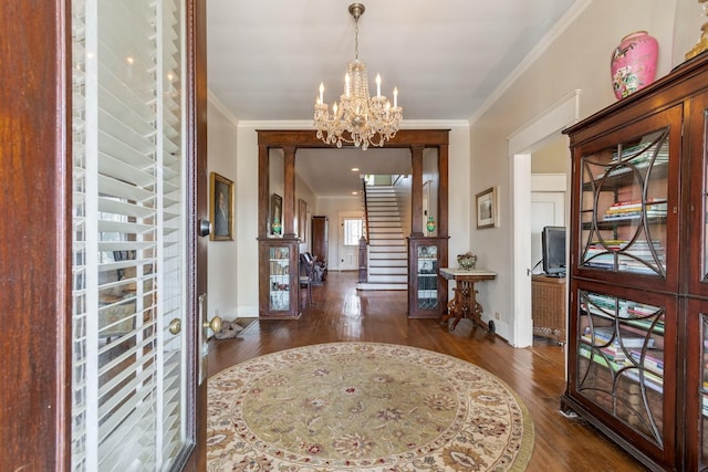 foyer entrance featuring crown molding, baseboards, wood finished floors, and a notable chandelier