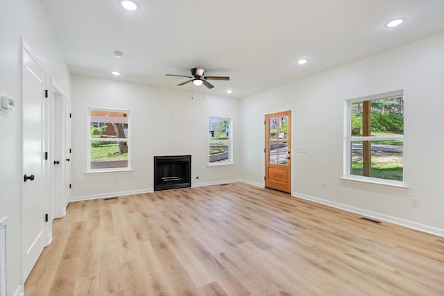 unfurnished living room featuring ceiling fan, visible vents, a healthy amount of sunlight, and a fireplace