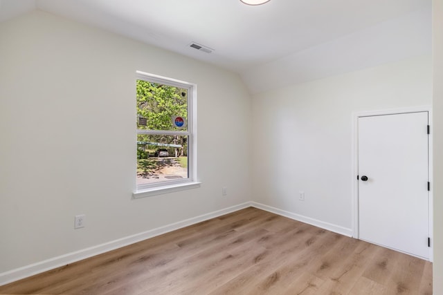 spare room with visible vents, baseboards, lofted ceiling, and light wood-type flooring