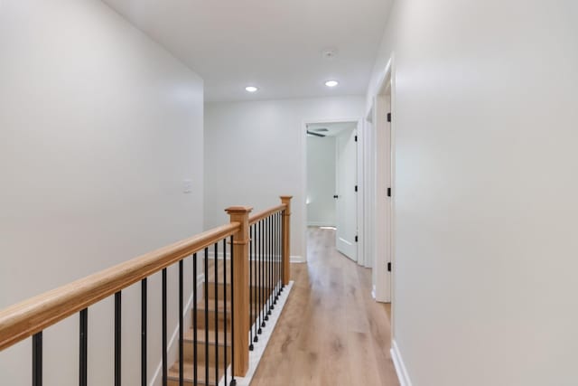 hallway with light wood-style floors, baseboards, recessed lighting, and an upstairs landing