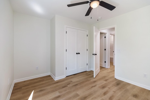 unfurnished bedroom featuring a ceiling fan, baseboards, light wood finished floors, and a closet