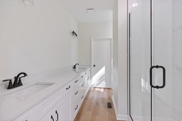 full bath featuring a sink, a stall shower, and wood finished floors