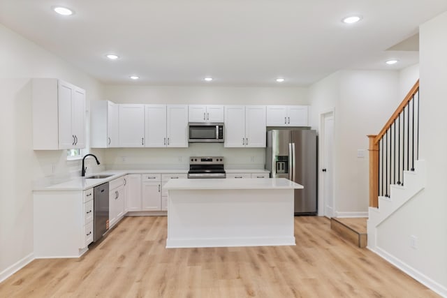 kitchen with a center island, a sink, light wood-style floors, and stainless steel appliances