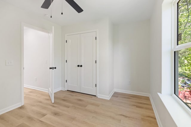 unfurnished bedroom featuring baseboards, multiple windows, ceiling fan, and light wood-style floors