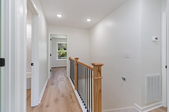 corridor featuring light wood-style flooring, recessed lighting, baseboards, an upstairs landing, and visible vents