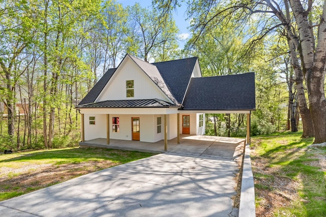 modern farmhouse with covered porch, a standing seam roof, driveway, a shingled roof, and an attached carport