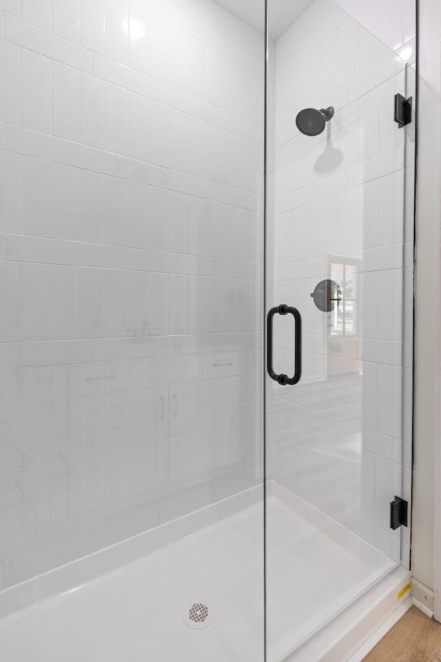 bathroom with wood finished floors and a stall shower
