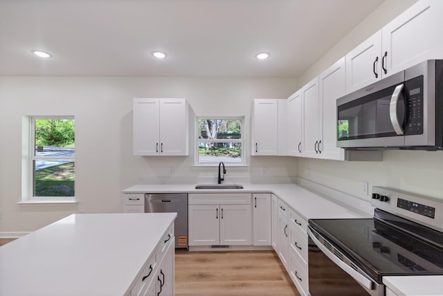kitchen featuring a sink, appliances with stainless steel finishes, white cabinetry, and light countertops