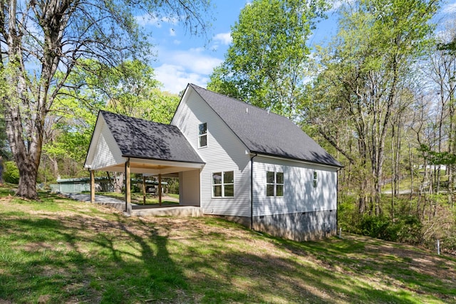 rear view of house featuring a lawn and roof with shingles