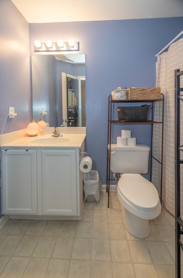 bathroom featuring curtained shower, vanity, toilet, and baseboards