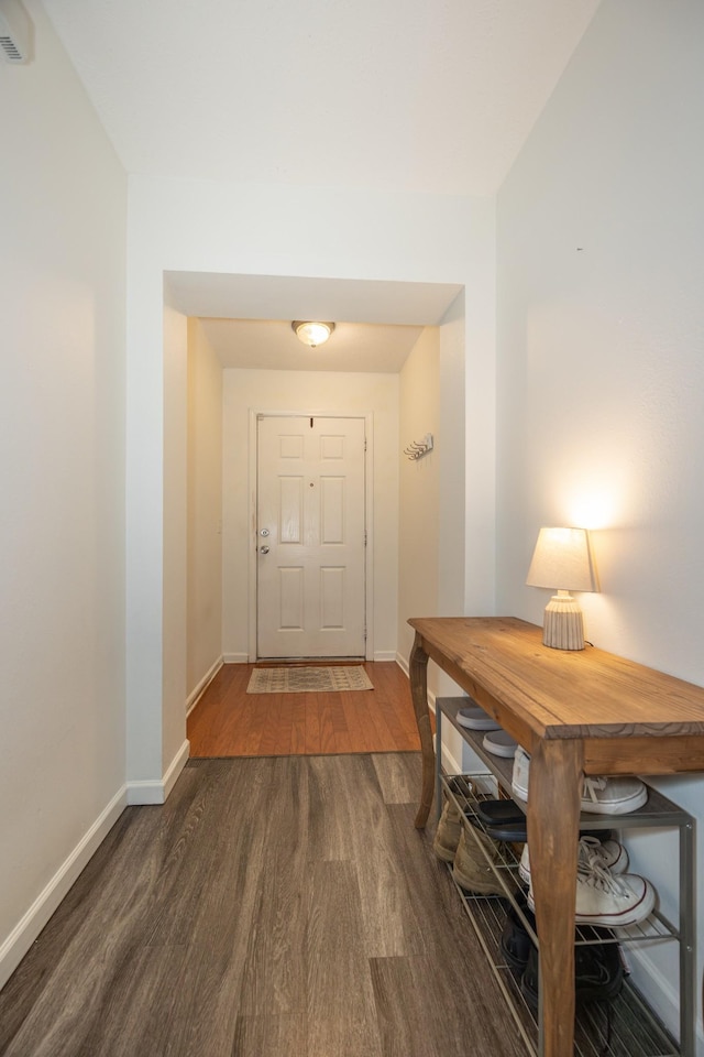 doorway to outside featuring baseboards and dark wood-style floors