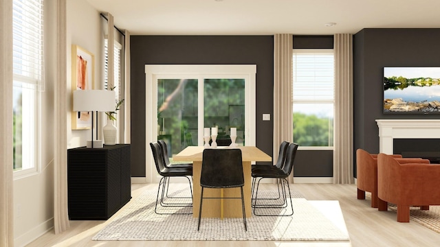 dining space featuring light wood-type flooring, baseboards, a healthy amount of sunlight, and a fireplace