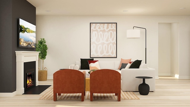 sitting room featuring baseboards, a fireplace with flush hearth, and wood finished floors