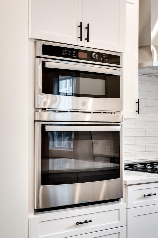 2509B Scovel St, Nashville, TN 37208 - interior details with white cabinets, black gas stovetop, double oven, wall chimney exhaust hood, and backsplash