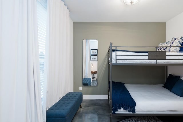 bedroom with finished concrete flooring and baseboards