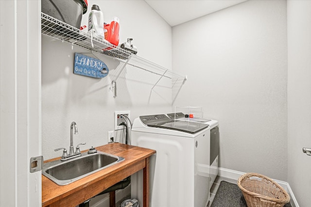 laundry area with a sink, baseboards, laundry area, and washer and dryer