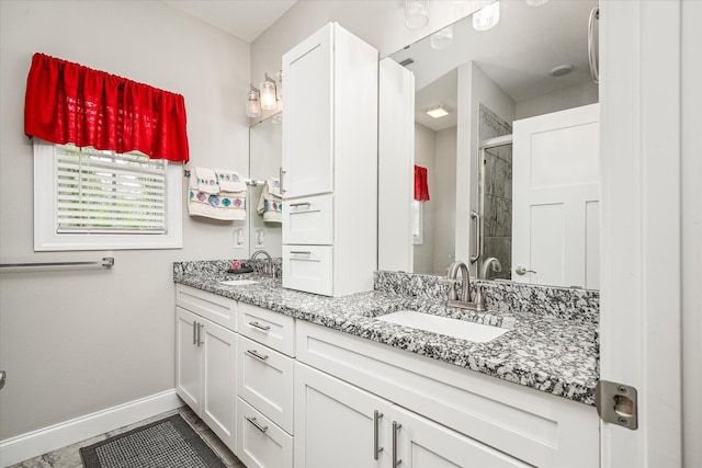 bathroom with a sink, baseboards, a shower stall, and double vanity
