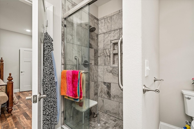 full bathroom featuring baseboards, a stall shower, toilet, and wood finished floors