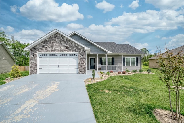 view of front of home with a porch, driveway, a front yard, a garage, and stone siding