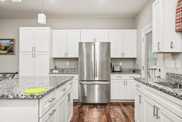 kitchen with freestanding refrigerator, white cabinetry, dark wood finished floors, and light stone counters