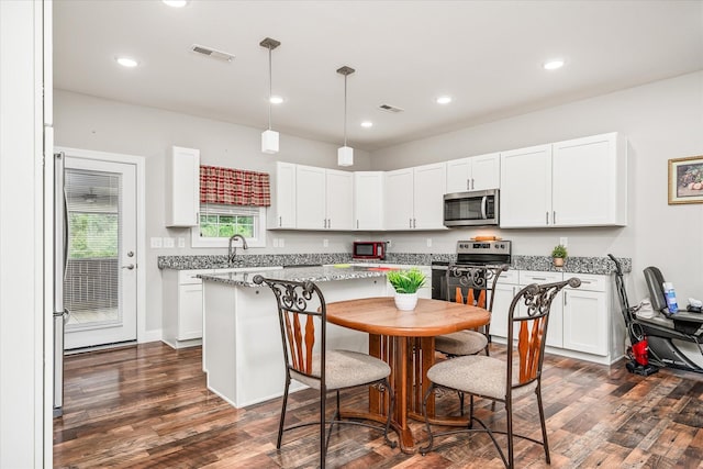 kitchen featuring white cabinets, stainless steel appliances, visible vents, and dark wood-style floors