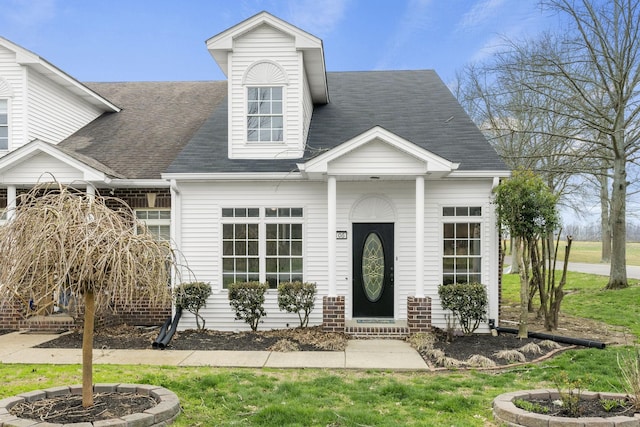 new england style home with a shingled roof and a front lawn