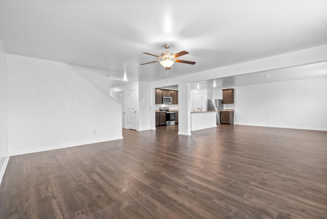 unfurnished living room with ceiling fan, dark wood finished floors, and baseboards