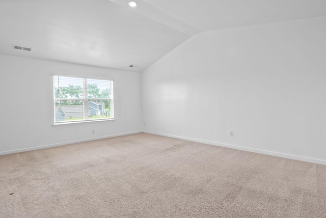 spare room with vaulted ceiling, baseboards, and light colored carpet