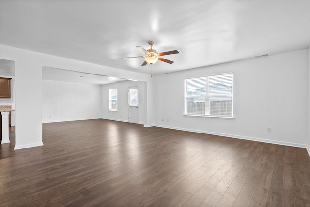 unfurnished living room with ceiling fan, dark wood finished floors, and baseboards