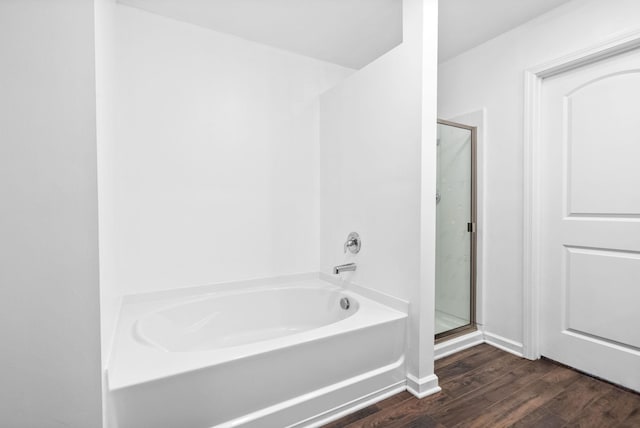 bathroom featuring a stall shower, a bath, and wood finished floors