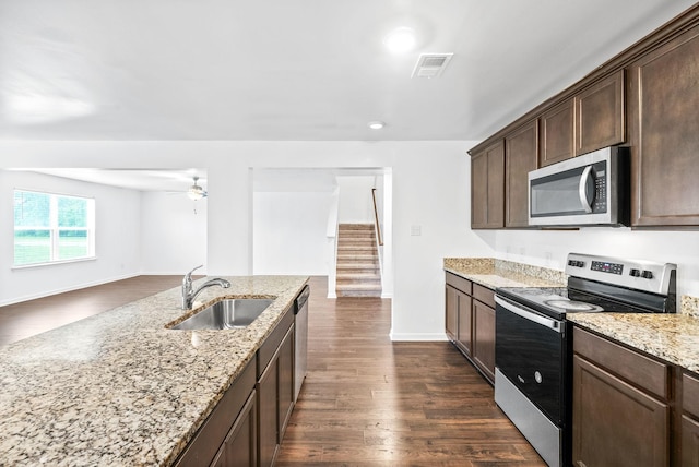 kitchen featuring appliances with stainless steel finishes, a sink, ceiling fan, dark brown cabinets, and dark wood finished floors