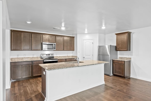 kitchen featuring stainless steel appliances, a sink, dark wood-style floors, recessed lighting, and light stone counters