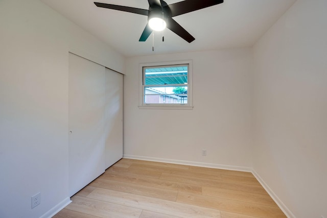 unfurnished bedroom with light wood-type flooring, baseboards, ceiling fan, and a closet
