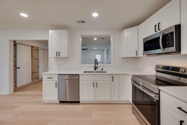 kitchen featuring light wood-style flooring, appliances with stainless steel finishes, a sink, and visible vents