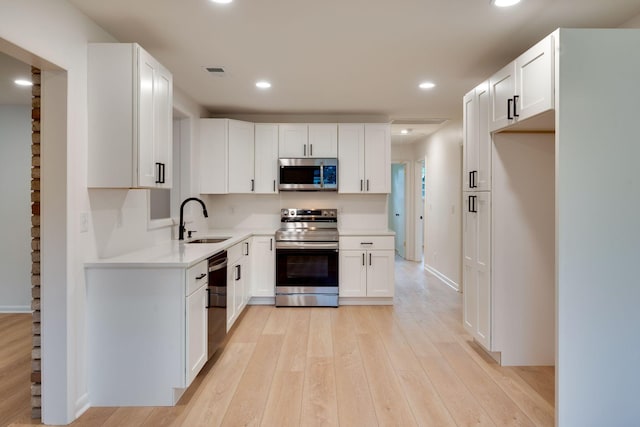 kitchen featuring recessed lighting, light countertops, a sink, light wood finished floors, and appliances with stainless steel finishes
