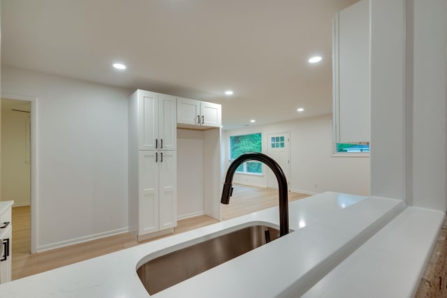 kitchen with light countertops, white cabinetry, recessed lighting, and a sink