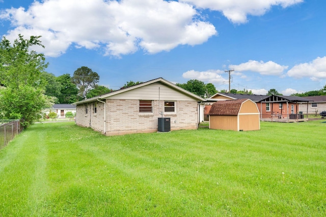 rear view of property featuring fence, a shed, cooling unit, an outdoor structure, and a yard