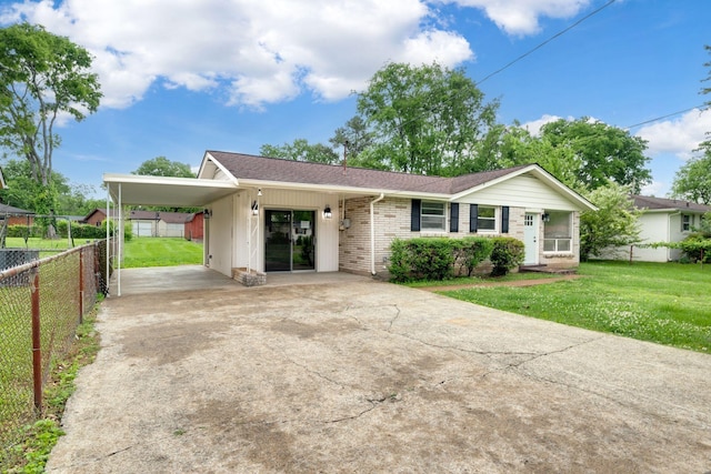 ranch-style house featuring fence, a front yard, an attached carport, brick siding, and driveway