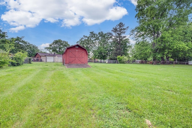 view of yard featuring a barn, fence, and an outbuilding