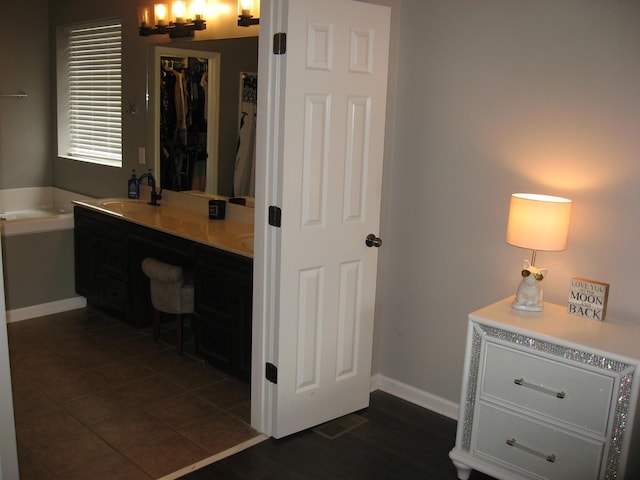 full bath featuring baseboards, a sink, a garden tub, and double vanity