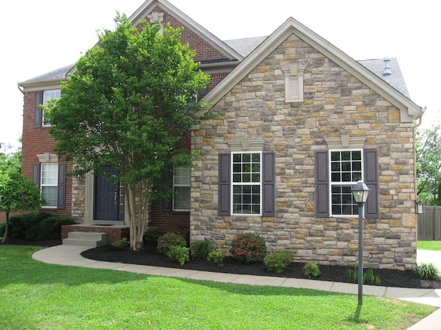 craftsman-style house featuring brick siding, stone siding, and a front yard