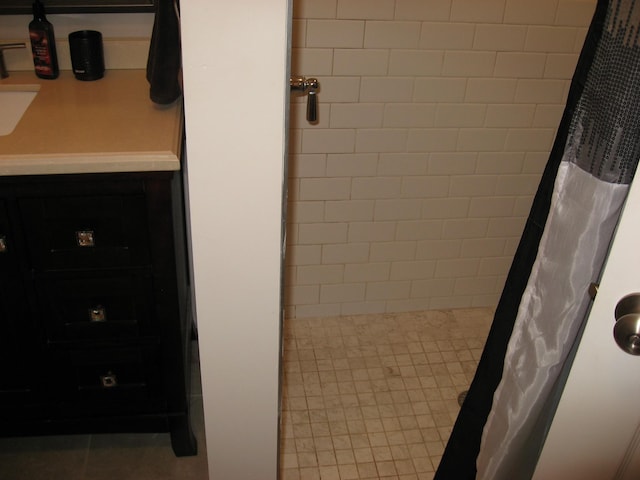 full bath featuring a tile shower and a sink