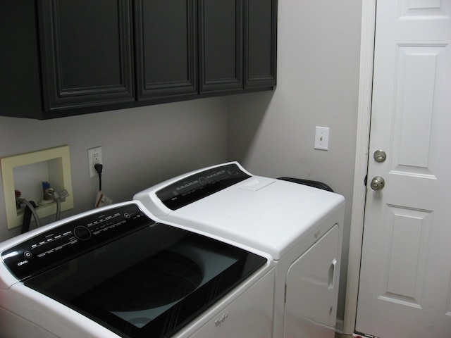 clothes washing area with separate washer and dryer and cabinet space
